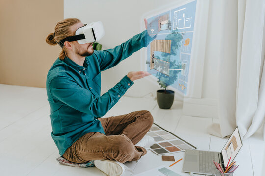 Interior designer preparing project through VR glasses sitting on floor at office