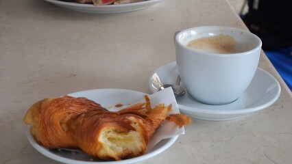 Delicious Golden Croissant with a Refreshing Cup of Coffee on a Textured Tabletop Perfect for a Morning Breakfast Scene