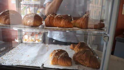 Delicious freshly baked golden brown croissants and pastries displayed in a clear glass bakery case...