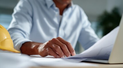 Engineer analyzing structural plans with computer and paper documents side by side
