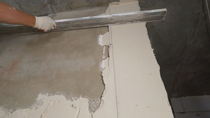 Construction worker applying plaster on the wall using a spatula and leveling the surface