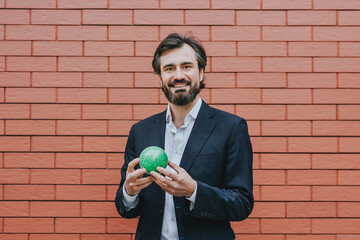 Businessman holding puzzle sphere in front of brick wall