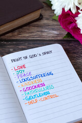 Fruit of God's spirit, handwritten Christian text in a notebook with holy bible book. Spiritual gifts: love, joy, peace, biblical concept.