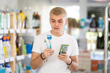 Male shopper chooses best toothbrush in supermarket