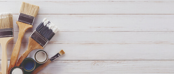 Several DIY paint supplies are placed on a white wooden background.
