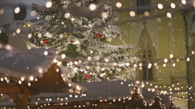 Snowfall creates magical ambiance at holiday market with festive lights and decorated Christmas tree in charming town square. First snow in city for new year holidays