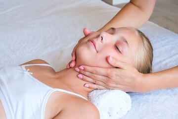 A woman gives a facial massage to a girl
