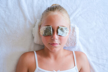 Beautiful girl with tea bags on eyes. Top view.