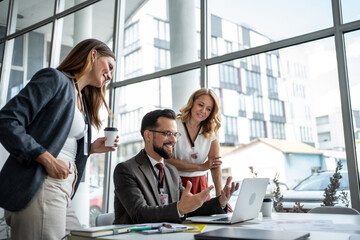 Fototapeta premium Business team discussing work on laptop in modern office