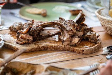 Juicy grilled meat ribs served on wooden platter during meal. Rustic presentation of seasoned barbecue with visible herbs and juicy texture, perfect for lunch or outdoor gathering.