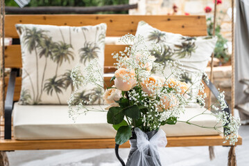 Elegant garden seating with blush-toned roses and baby’s breath beside tropical-themed pillows. Serene floral vibe ideal for outdoor events, weddings, or intimate summer moments.