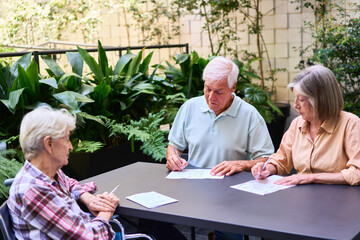 Senior individuals solving puzzles together in an outdoor lush setting