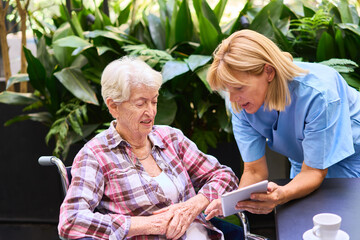Caregiver Assisting Elderly Woman Outdoors with a Tablet Device