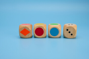 Four wooden dice with vibrant colors and simple shapes colored circles, a diamond shape, and number...
