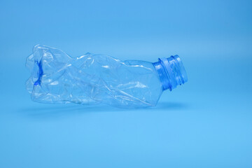 A single crushed plastic bottle placed on a clean blue background symbolizes plastic waste, recycling. Suitable for sustainability, waste management, educational