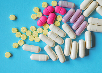 Assorted pharmaceutical medicine pills, tablets and capsules on blue background, top view