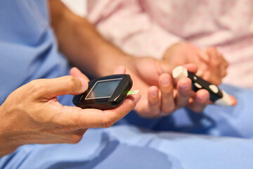 Close-up of hands using a glucometer for blood glucose testing