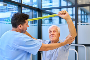 Senior patient assisted in rehabilitation exercise with supportive medical professional