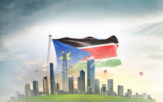 South Sudan national flag wavering with modern building skyline. Country showing stronger and prosperity. Flag key visual. Sudan national flag for independence day.