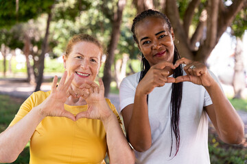 Diverse women creating heart shape with hands, expressing connection, warmth, and solidarity in...