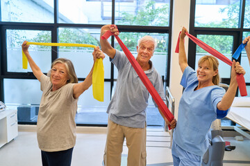 Elderly individuals exercising with therapist in a senior rehabilitation facility room