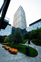 Modern glass building with landscaped green area and orange seating features