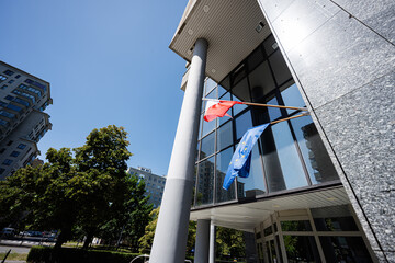 Modern glass building with national and European flags on a sunny day