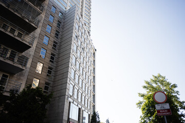 Modern urban building with clear sky and signboard against green trees landscape
