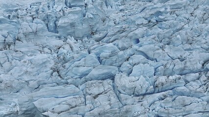 Aerial view of a vast expanse of glacial ice, its surface a labyrinth of crevasses and ridges tinted in shades of pale blue and grey, Chile.