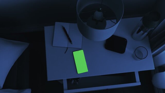 vibrating smartphone with greenscreen lying on a nightstand, illuminated by moonlight
