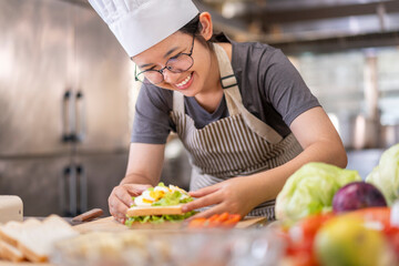Smiling Young Female Chef Preparing a Sandwich in a Professional Kitchen