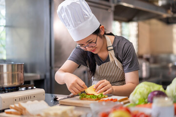 Smiling Young Female Chef Preparing a Sandwich in a Professional Kitchen