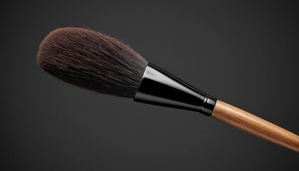 Close-up of a luxurious makeup brush with soft, dark bristles, a sleek black ferrule, and a polished bamboo handle against a dark gray background.