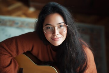 Young asian female playing guitar in cozy room with warm lighting