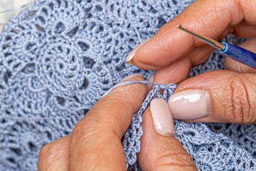 Close up of hands of unrecognizable woman knitting handmade clothes with spokes using  wool yarn....