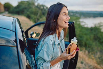 Happy tourist savoring a delicious burger and sipping on refreshing juice during a scenic road trip...