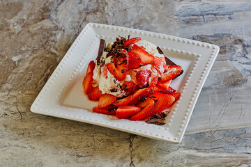 strawberry cheesecake trifle with fresh strawberries, shaved chocolate, and whipped cream, plated