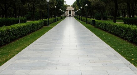 Marble path leads toward archway, flanked by manicured greenery in a park, beneath leafy canopy