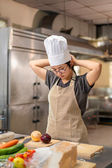 Young Asian Female Chef Adjusting Hat in Professional Kitchen