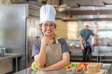 Young Female Chef Smiling in Professional Kitchen with Arms Crossed
