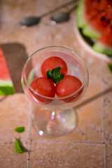 Glass filled with frozen watermelon spheres, resembling sorbet or ice cream. Concept of summer beverages, fruit cocktails, and healthy lemonades.