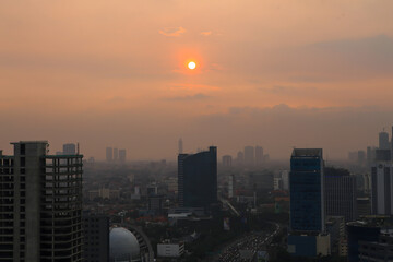 Jakarta City Skyline at Sunset with Orange Hazy Sky and Urban Buildings