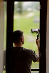 A man records a video on his phone for a blog, uses a stabilizer