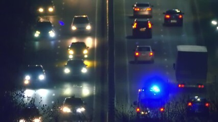 Car lights and parking lights in night traffic on all lanes of the highway going up, where an ambulance with flashing blue lights is going to the hospital - Powered by Adobe