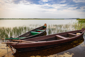 Wooden boat with oars on the shore of a lake against the backdrop of a beautiful landscape.