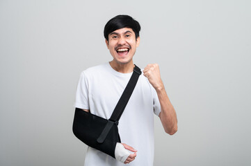 An Asian man in a hospital gown smiles gently at the camera, arm bandages and bandages on his arm,...