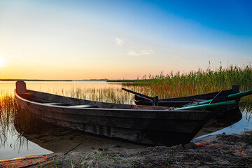 Traditional wooden fishing boat with oars on the lake shore.