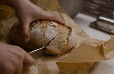 Freshly baked bread being cut on a baking paper