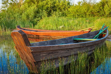 Traditional wooden fishing boat with oars on the lake shore.