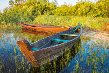 Traditional wooden fishing boat with oars on the lake shore.